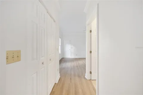 a view of a hallway with wooden floor and a bathroom