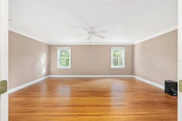 a view of an empty room with wooden floor and a window