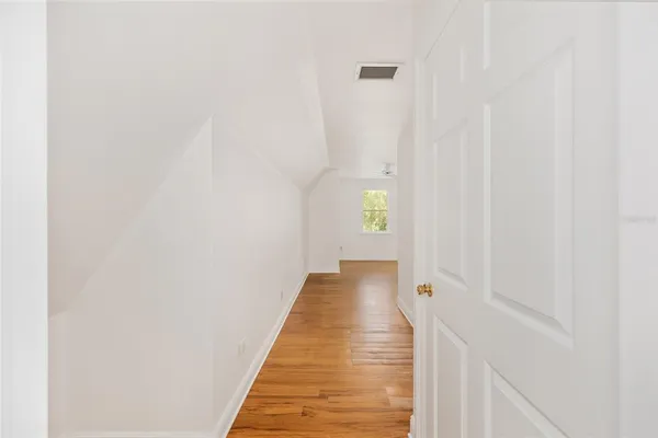 an empty room with wooden floor ceiling fan and windows