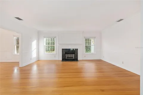 a view of empty room with wooden floor and fireplace