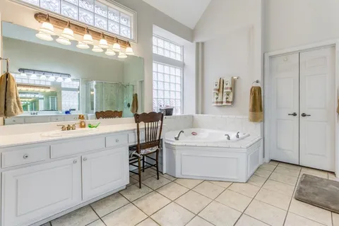a spacious bathroom with a tub a sink and mirror