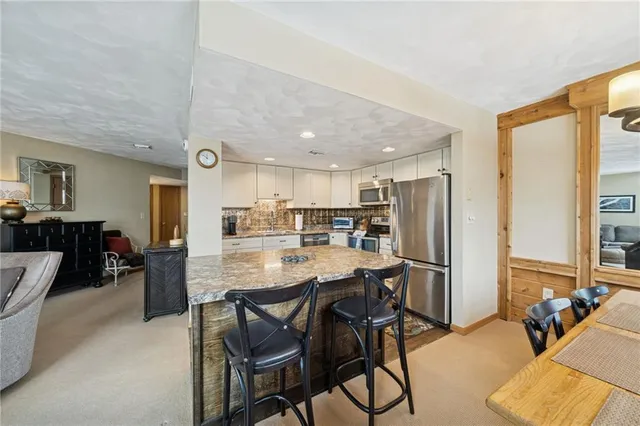 a kitchen with a dining table chairs cabinets and stainless steel appliances