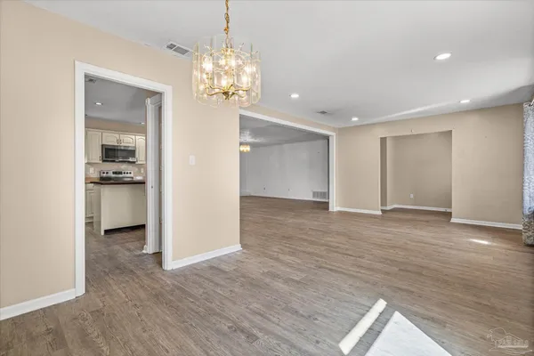 a view of a hallway with wooden floor and chandelier