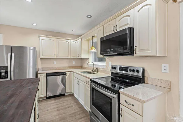 a kitchen with stainless steel appliances a sink a stove a microwave a sink and cabinets