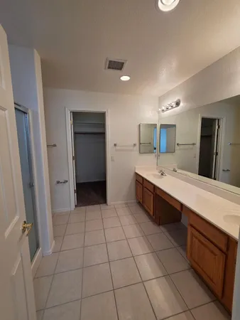 a spacious bathroom with a double vanity sink a mirror and a bathtub
