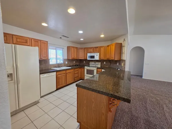 a kitchen with stainless steel appliances granite countertop a refrigerator a sink a stove a microwave and island