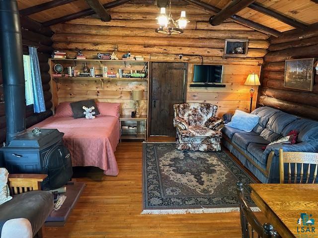 615 Kellys Lot Road Ely, MN 55731 - Photo 11 of 39 Living room featuring vaulted ceiling with beams, a wood stove, hardwood / wood-style flooring, and rustic walls