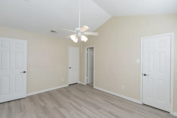 an empty room with wooden floor and ceiling fan