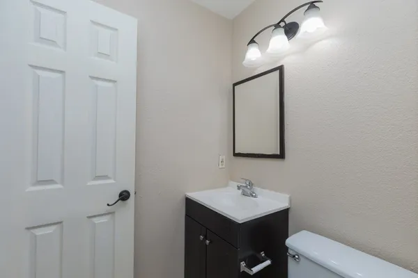 a bathroom with a toilet sink vanity and mirror
