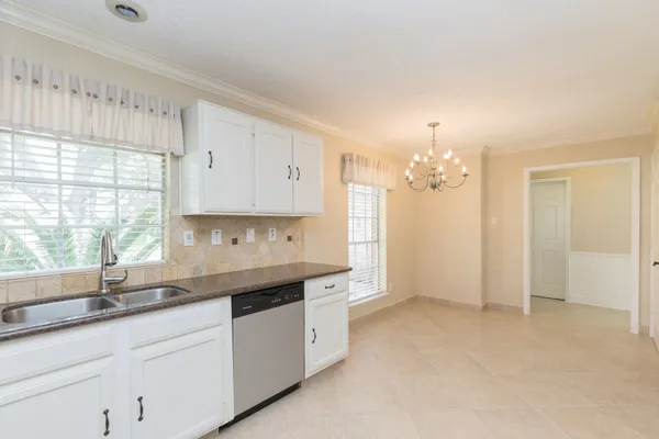 a kitchen with granite countertop white cabinets white appliances a sink and a window