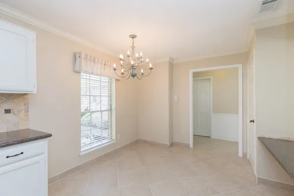 a view of an empty room with chandelier and a window