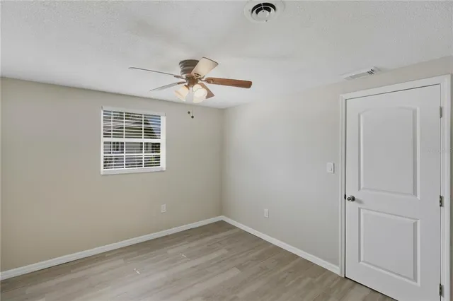 a view of empty room with wooden floor and fan