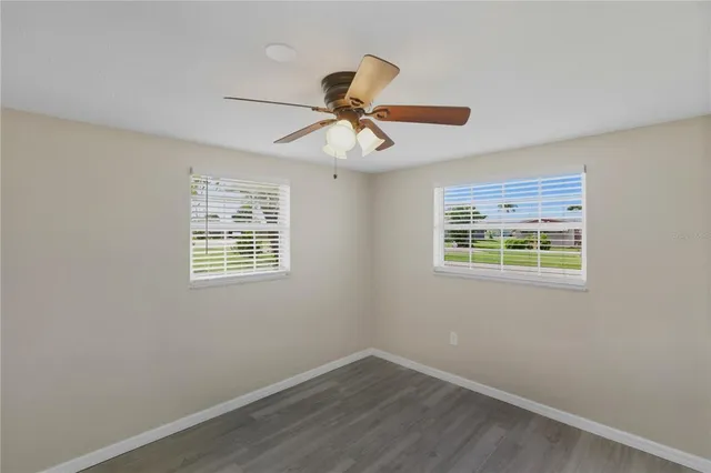 a view of an empty room with window and wooden floor