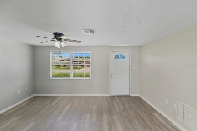 a view of an empty room with a window and wooden floor