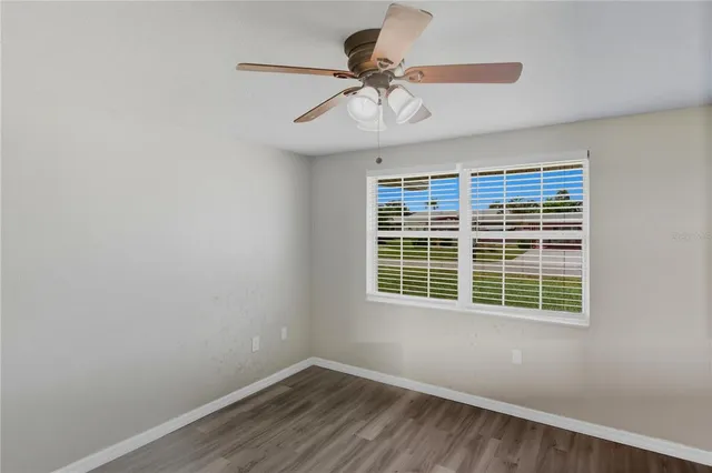 an empty room with a window and a fan