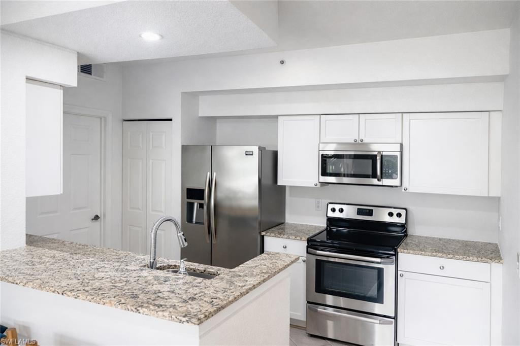 4635 St Croix Lane, Unit 1222 Naples, FL 34109 - Photo 5 of 20 a kitchen with stainless steel appliances granite countertop a refrigerator and a sink