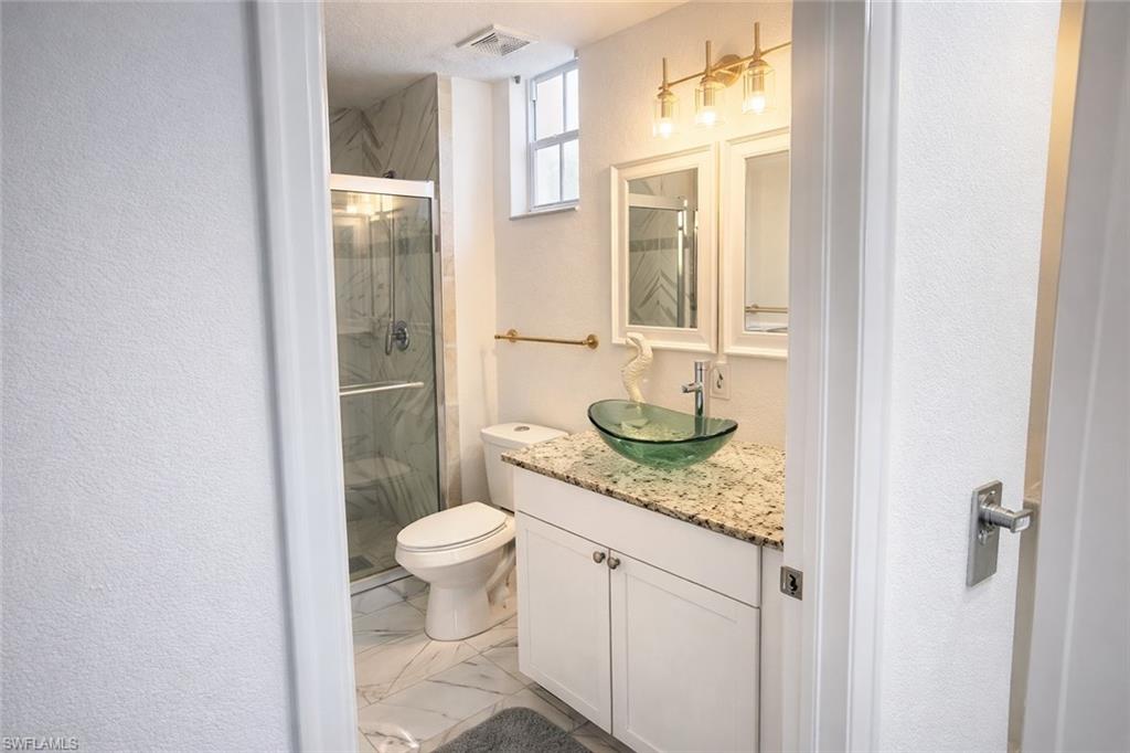 4635 St Croix Lane, Unit 1222 Naples, FL 34109 - Photo 10 of 20 a bathroom with a granite countertop sink toilet and shower