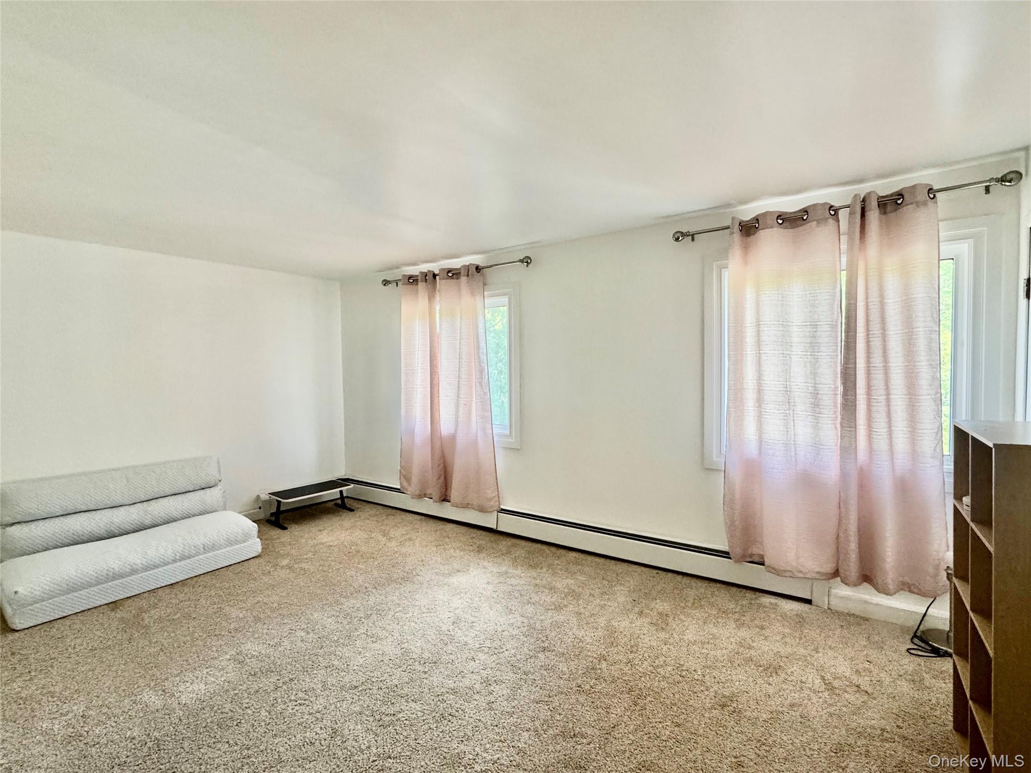 17 North Aspen Road Middletown, NY 10940 - Photo 11 of 12 Large bedroom with light carpet and a baseboard heating unit