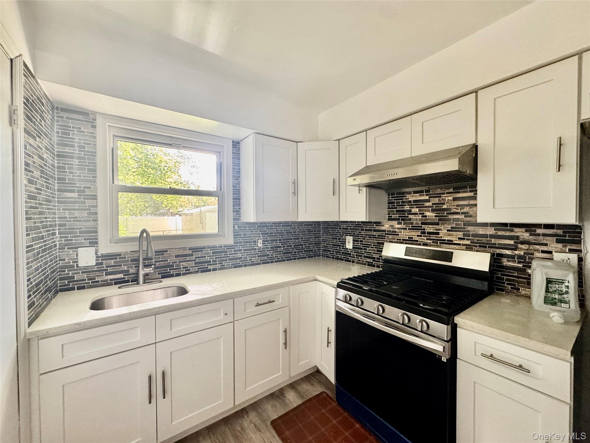 17 North Aspen Road Middletown, NY 10940 - Photo 7 of 12 Kitchen with stainless steel range with gas cooktop, white cabinetry, tasteful backsplash, and exhaust hood