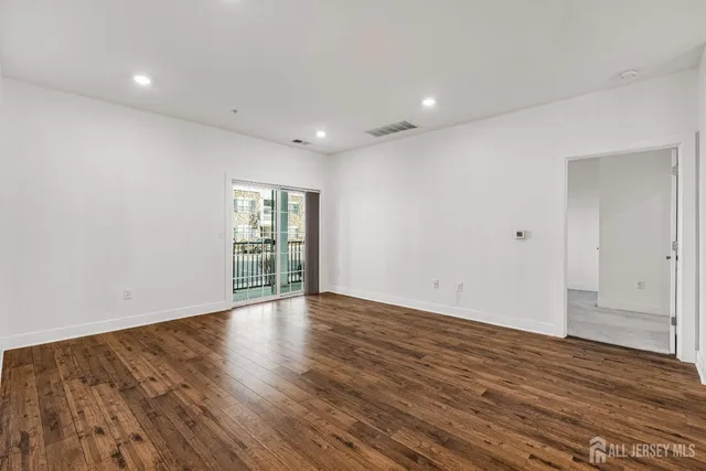 a view of an empty room with wooden floor and window