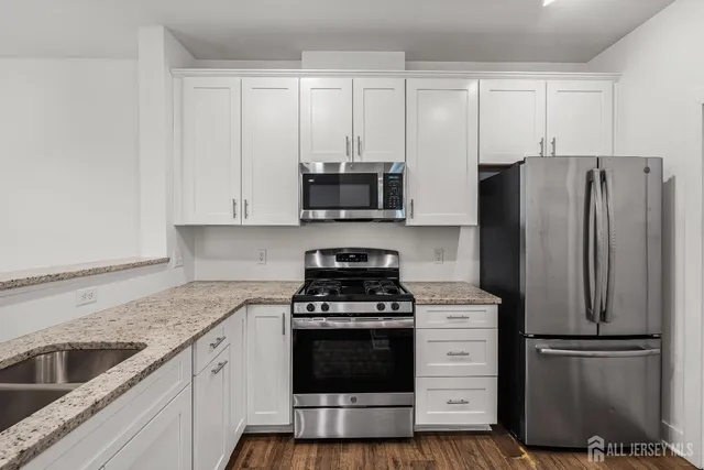 a kitchen with cabinets stainless steel appliances and wooden floor
