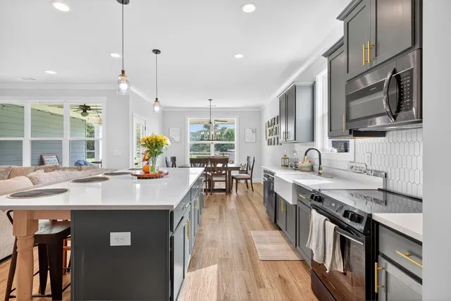 a kitchen with stainless steel appliances granite countertop a sink stove a oven a dining table and chairs with wooden floor