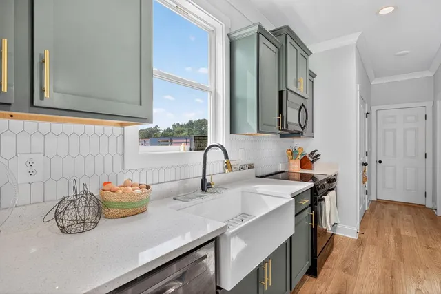 a kitchen with stainless steel appliances a sink dishwasher stove and cabinets with wooden floor