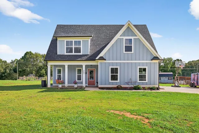 a front view of a house with garden and trees