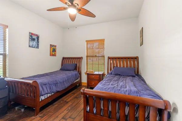 a bedroom with two beds and wooden floor