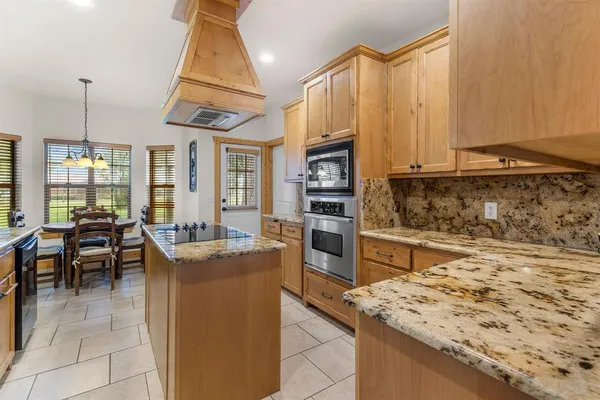 a kitchen with stainless steel appliances granite countertop a sink a stove counter space and cabinets