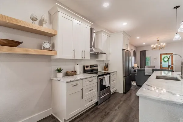 a kitchen with stainless steel appliances granite countertop a sink dishwasher and a dining table with wooden floor