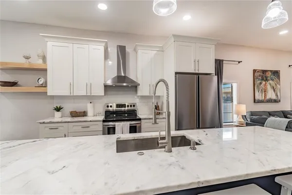 a dining room with stainless steel appliances furniture a large window and a kitchen view