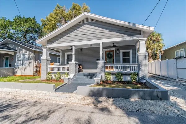 a front view of house with yard outdoor seating and covered with trees in the background