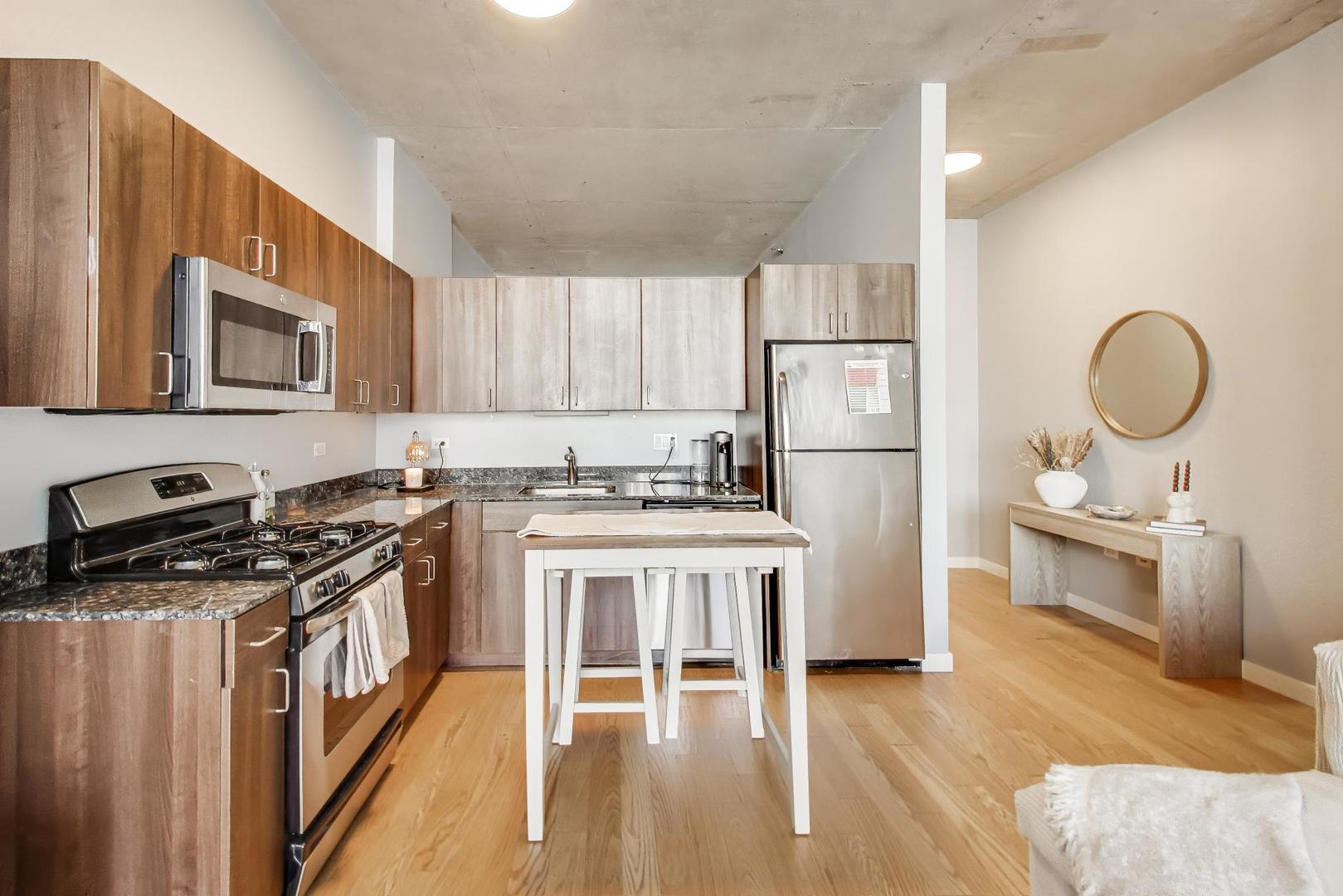 235 West Van Buren Street, Unit 2017 Chicago, IL 60607 - Photo 8 of 19 a kitchen with stainless steel appliances granite countertop a stove top oven a sink dishwasher a refrigerator and a dining table with wooden floor