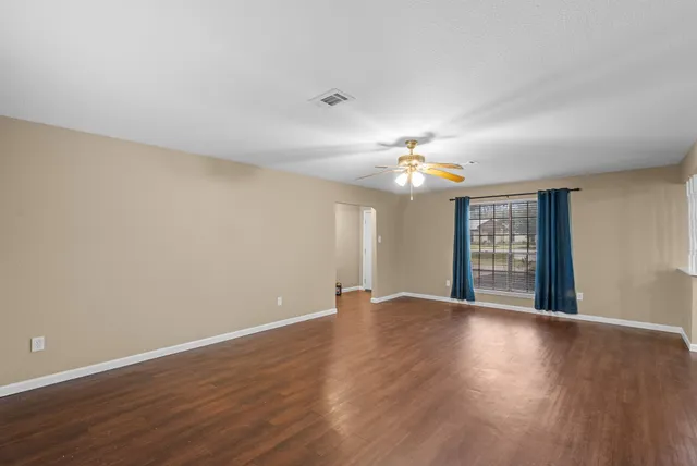 a view of an empty room with wooden floor and chandelier
