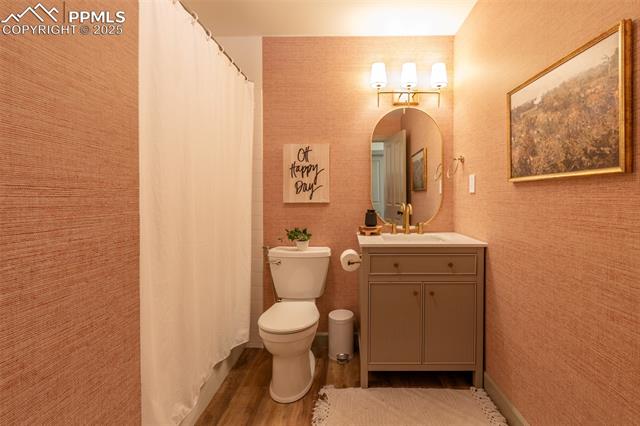 11170 Peaceful Valley Road Colorado Springs, CO 80925 - Photo 24 of 49 Full bath with vanity, wood finished floors, wallpapered walls, and curtained shower
