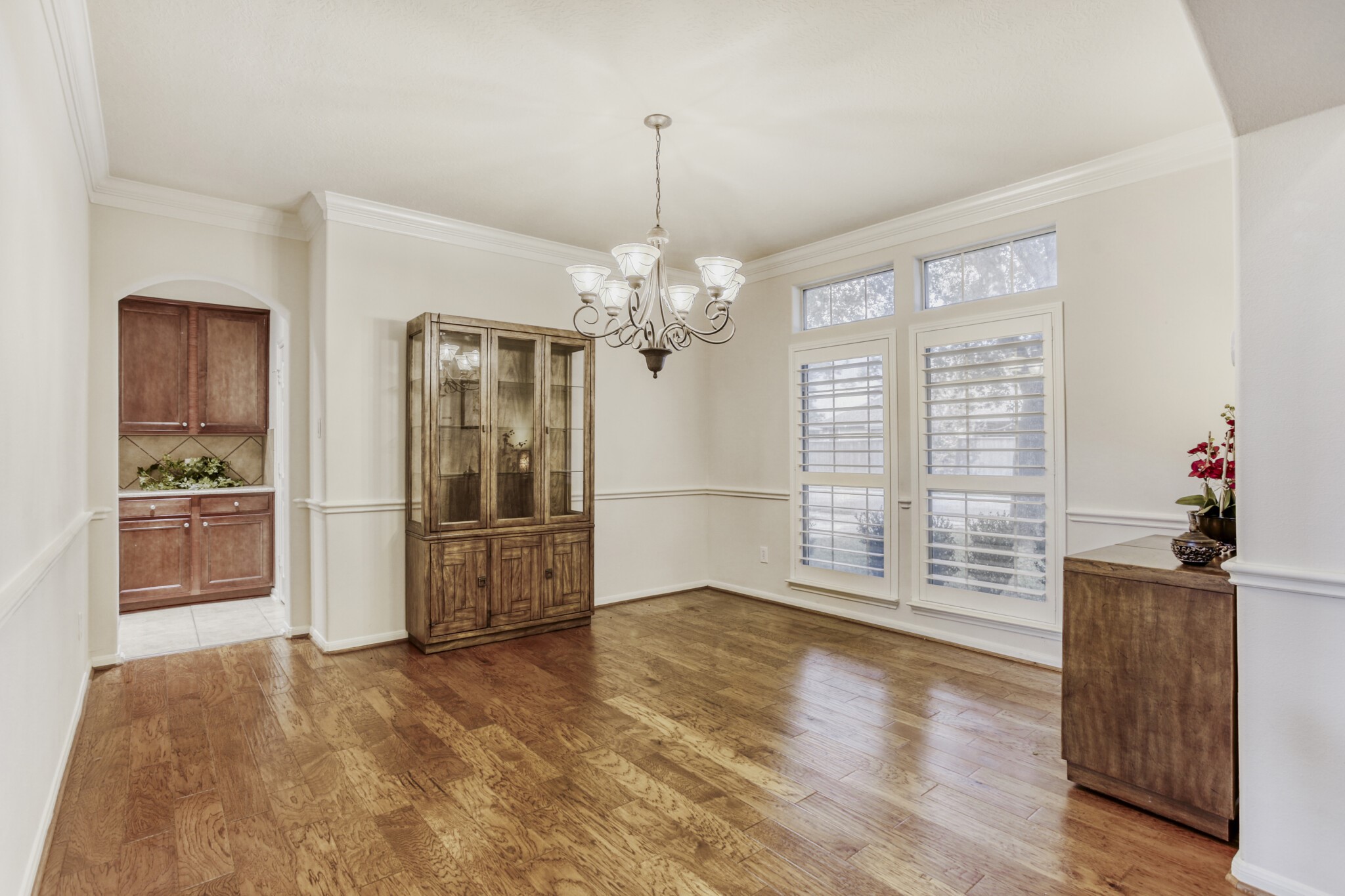 19303 Valiant Woods Drive Spring, TX 77379 - Photo 14 of 27 This elegant formal dining room boasts rich hardwood floors, a stately chandelier, and abundant natural light through plantation shutters, creating a perfect setting for memorable gatherings.