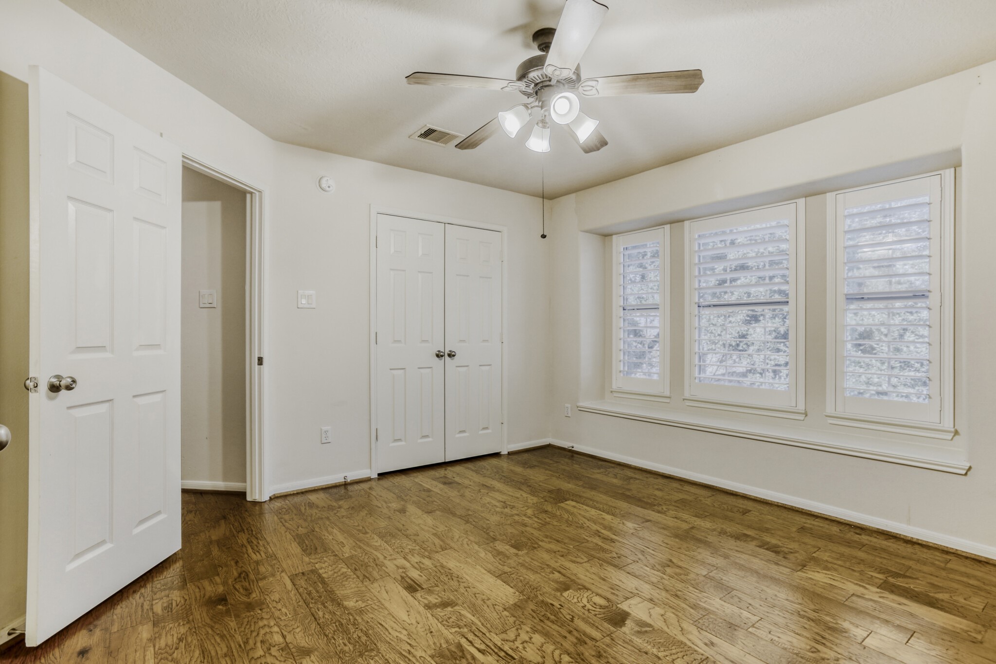 19303 Valiant Woods Drive Spring, TX 77379 - Photo 20 of 27 This inviting secondary bedroom features elegant wood floors, abundant natural light from large windows, and stylish plantation shutters, creating a cozy and serene retreat.