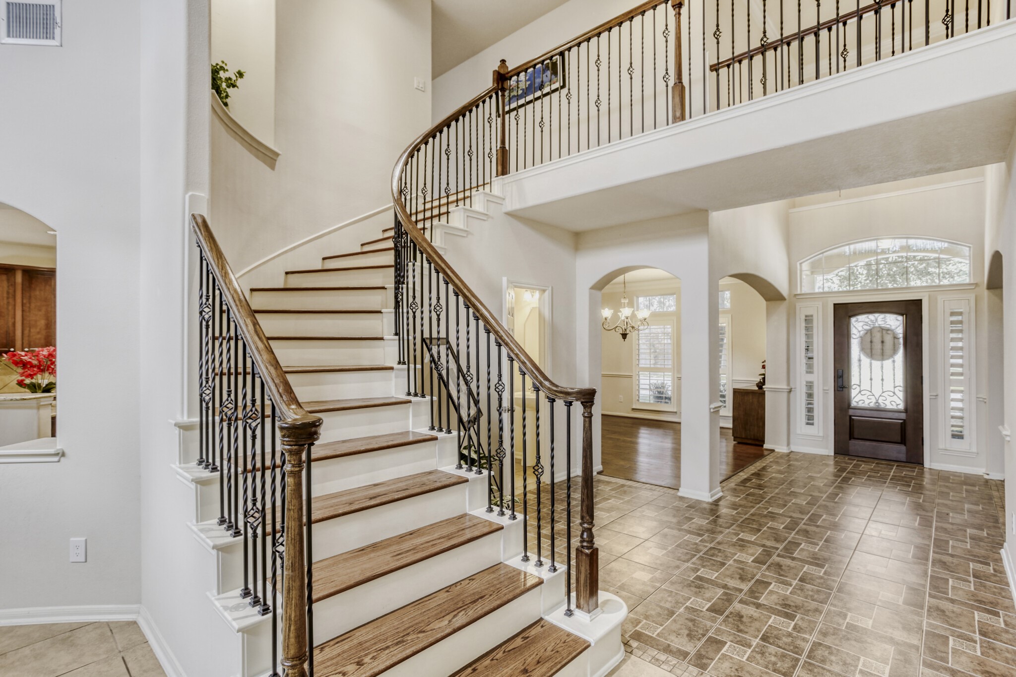 19303 Valiant Woods Drive Spring, TX 77379 - Photo 5 of 27 Discover elegance as you enter this home, featuring a stunning curved staircase with rich wood steps and intricate iron railings, setting a grand tone for your living space.