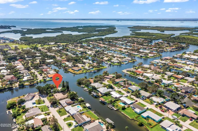an aerial view of a house with a yard lake and trees all around