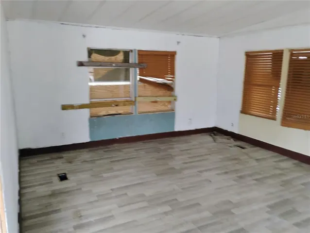an empty room with wooden floor and window