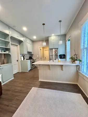 a kitchen with stainless steel appliances kitchen island granite countertop a refrigerator a stove and a wooden floors