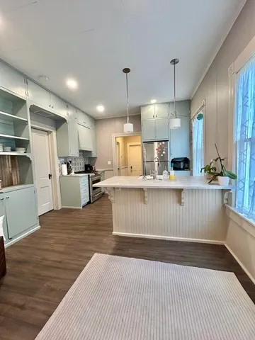 a kitchen with stainless steel appliances kitchen island granite countertop a refrigerator a stove and a wooden floors