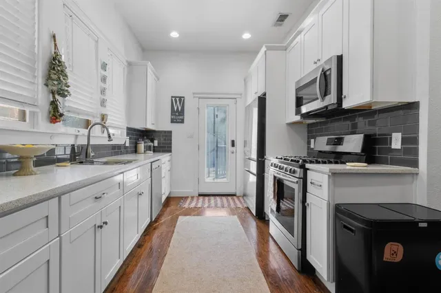 a large kitchen with stainless steel appliances granite countertop a stove a sink and a refrigerator