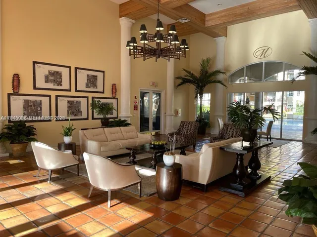 a living room with couches a chandelier and a dining table with wooden floor
