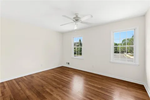 an empty room with wooden floor closet and windows