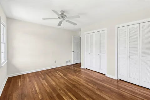 an empty room with wooden floor closet and fan