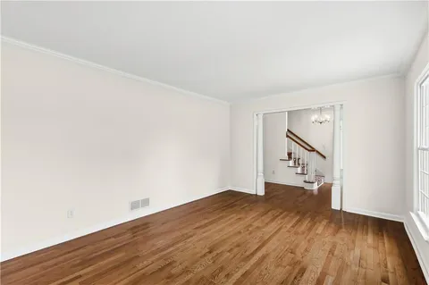 an empty room with wooden floor and stairs