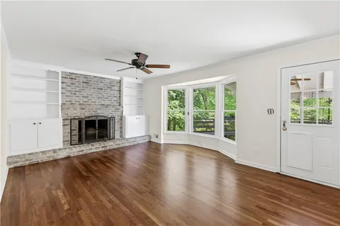 a view of an empty room with wooden floor fireplace and a window