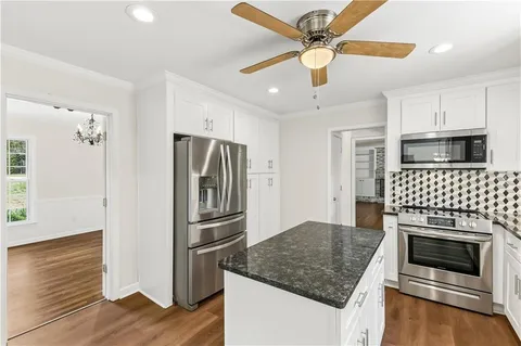 a kitchen with granite countertop a refrigerator oven a sink and a counter space